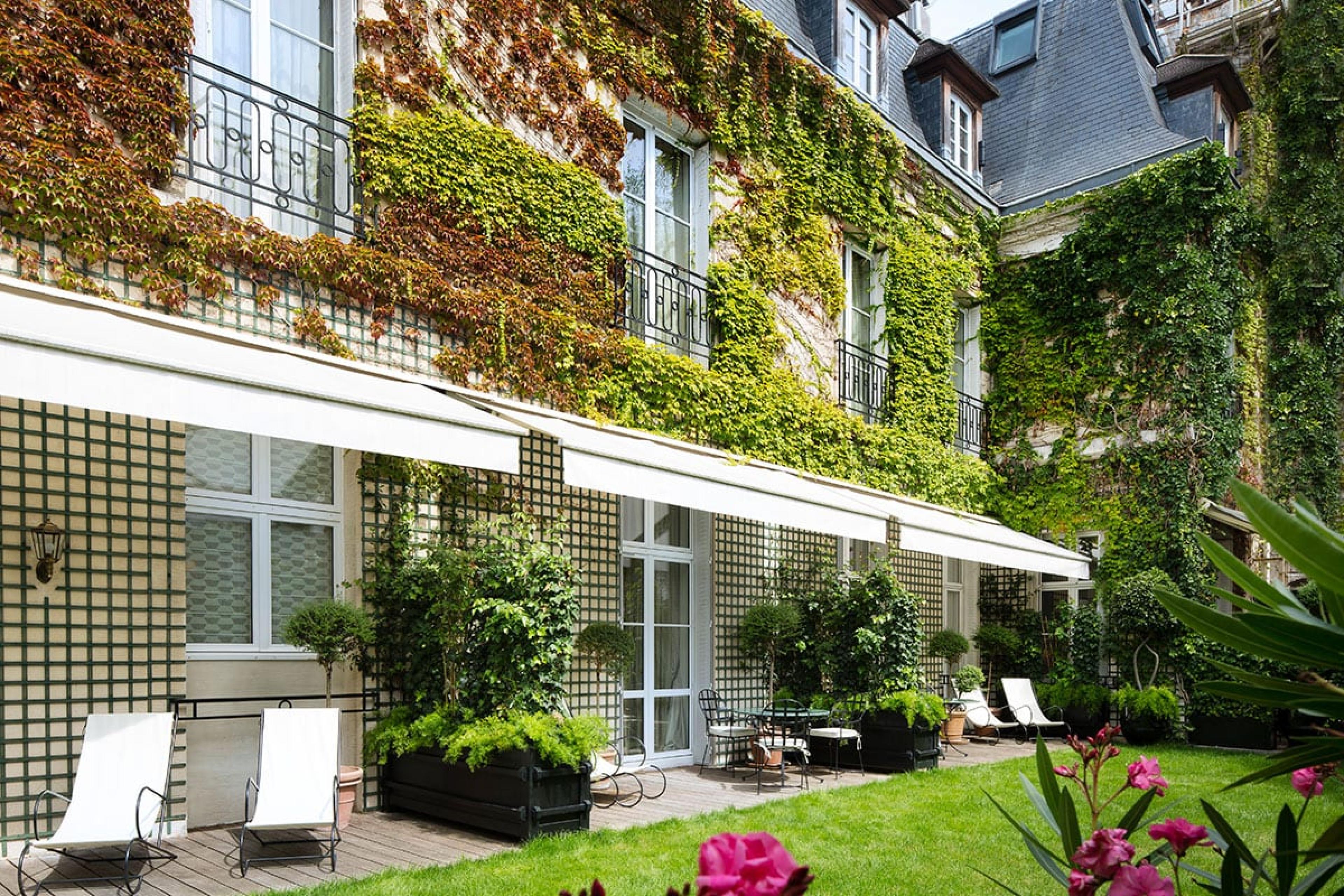 a private garden area with ivy-covered building and grass lawn